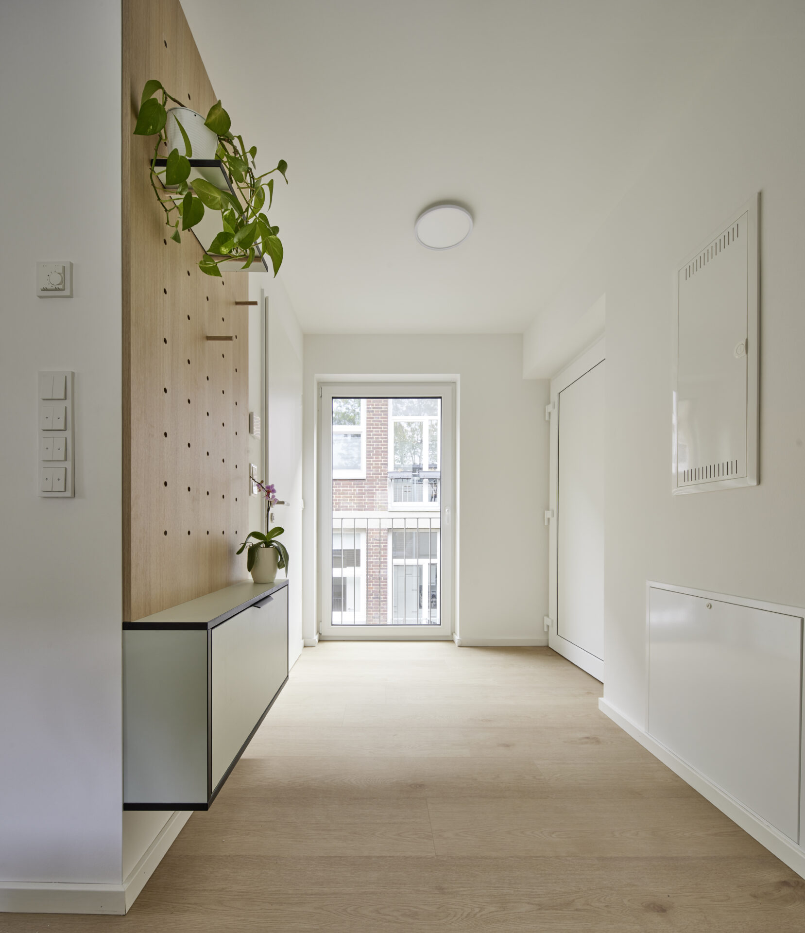Eingangsbereich mit Garderobe aus Holz und Balkonblick